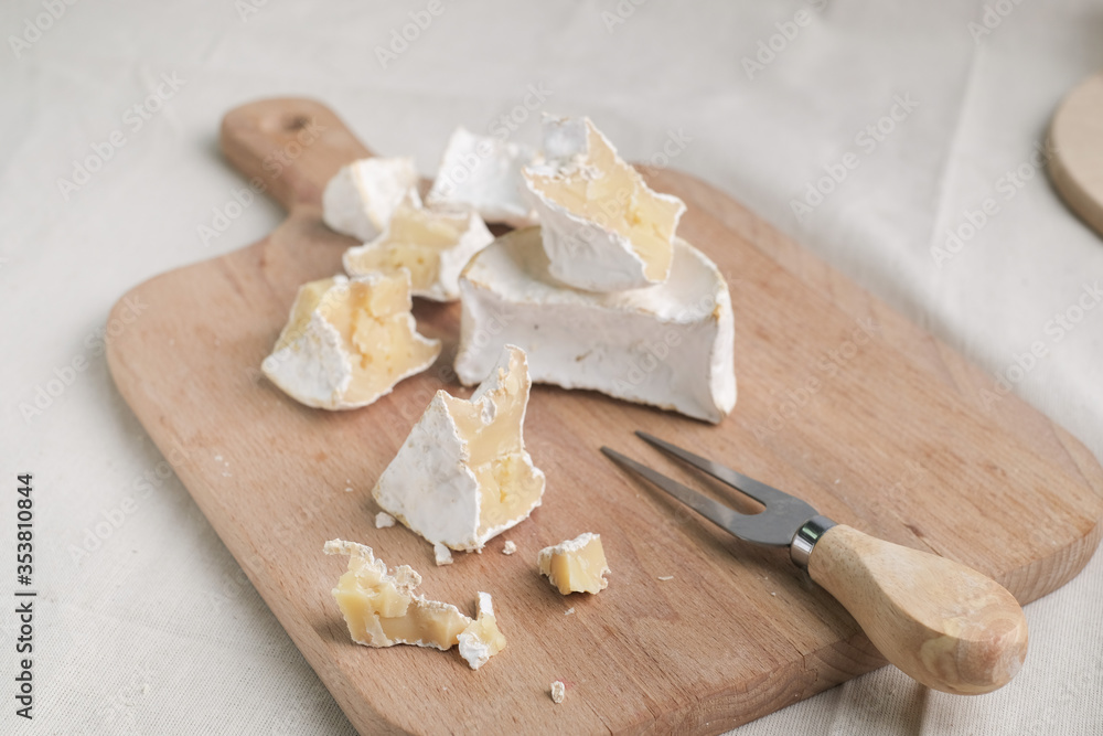 Fototapeta premium Homemade cheese on wooden plate at light background.