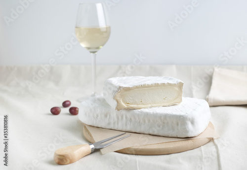 Homemade cheese on wooden plate at light background.