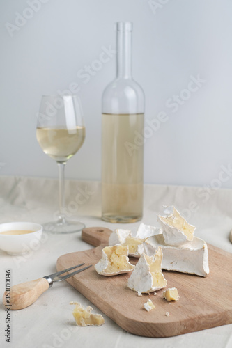 Homemade cheese on wooden plate at light background.