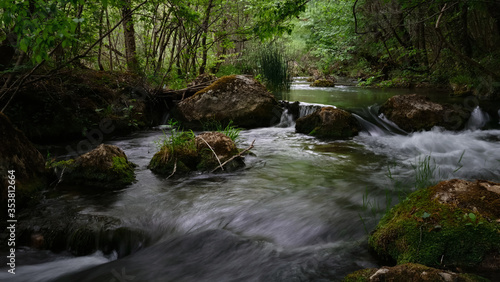 Full-flowing river in a green sunny forest.