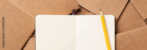 open notebook with pencil on brown kraft notebook disorder alignment on table background.mokcup template for diaplay content or design.content marketing concept photo