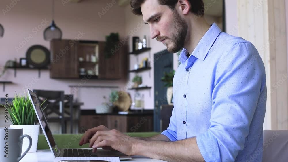 Side view happy young businessman is analizing financial documents from home during self isolation on laptop, sitting at table. Side view happy young businessman is analizing financial documents from home during self isolation on laptop, sitting at table.