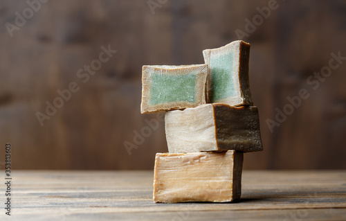 Two bars and slices of traditional aleppo organic laurel soap on a brown wooden background. photo