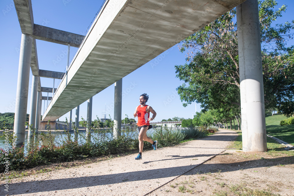 Fototapeta premium Hombre joven practicando running en el parque junto a un lago