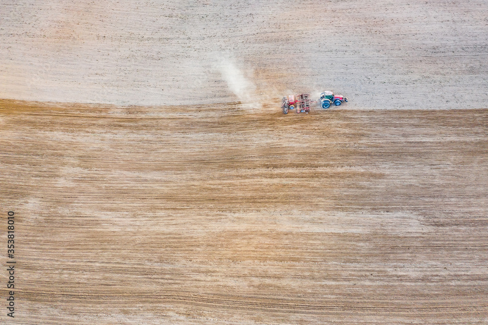 A tractor rides through a spring field. Field processing, drone shooting A tractor rides through a spring field. Field processing, drone shooting