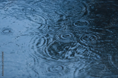 Raindrops on a water surface - a rainy weather background