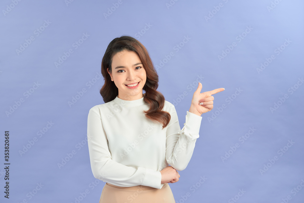 Young woman pointing at blank copy space, isolated over purple Young woman pointing at blank copy space, isolated over purple