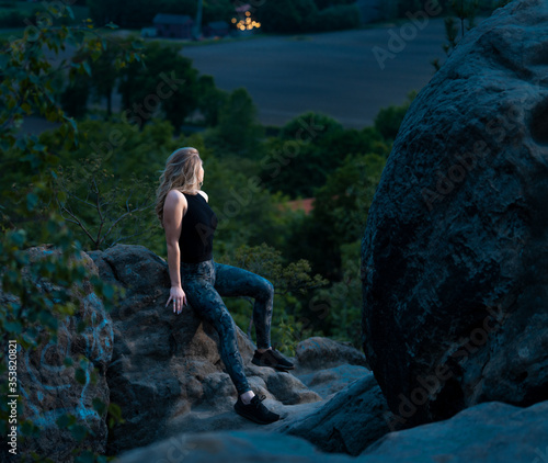 Sportliche Frau auf der Felswand beim wandern bewundert die Aussicht und Landschaft beim Sonnenuntergang.