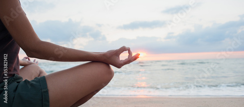 Young woman practicing yoga outdoors. Girl meditating with sunset sea view at background, panoramic banner. Harmony, meditation, relaxation, healthy lifestyle concept.