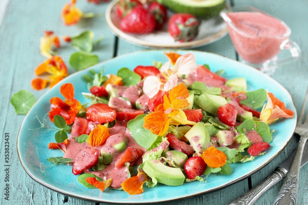 salad with nasturtium flowers and leaves with strawberries and avocados. dressed with strawberry vinaigrette or strawberry dressing with poppy seeds.
