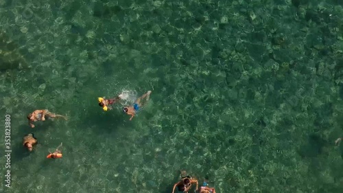 footage from top of a beautiful turquoise colored sea where people are swimming and having fun