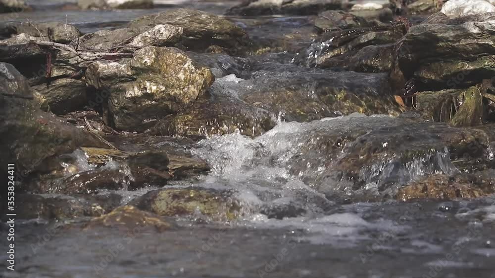 A freshwater stream with crystal clear water flows between the rocks. Close up A freshwater stream with crystal clear water flows between the rocks. Close up