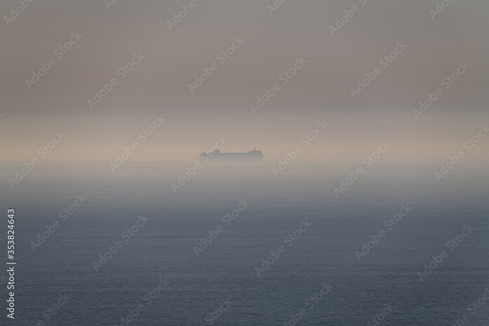 Naklejka premium A large ship in the sea mist off the coast of Cornwall in late Spring