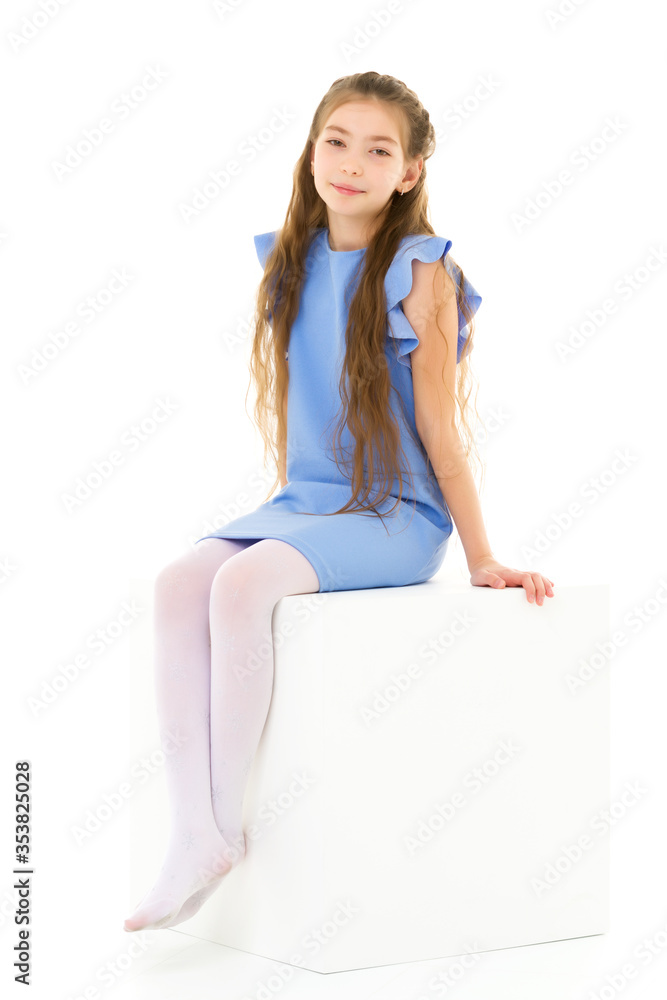 Little girl poses for a magazine in the studio on a white cube. Little girl poses for a magazine in the studio on a white cube.