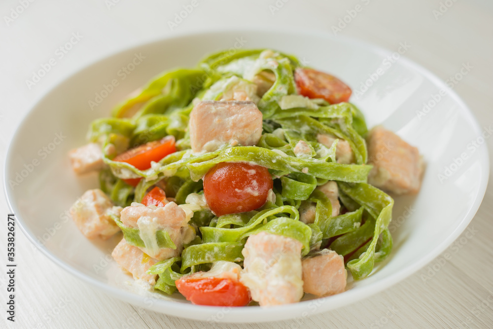 Close Up Spinach Tagliatelle pasta with salmon in cream sauce ready to eat. Mediterranean cuisine.