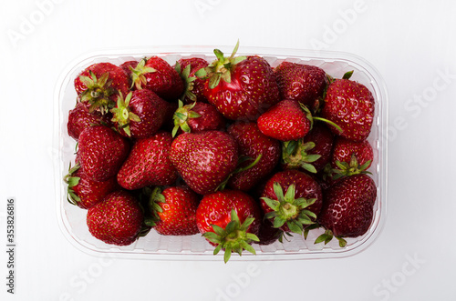 Top view of fresh juicy strawberries in the plastic container  white background