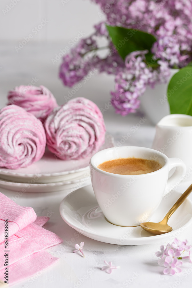 A cup of espresso with homemade berry marshmallows and a bouquet of lilacs on the table. Selective focus. A cup of espresso with homemade berry marshmallows and a bouquet of lilacs on the table. Selective focus.