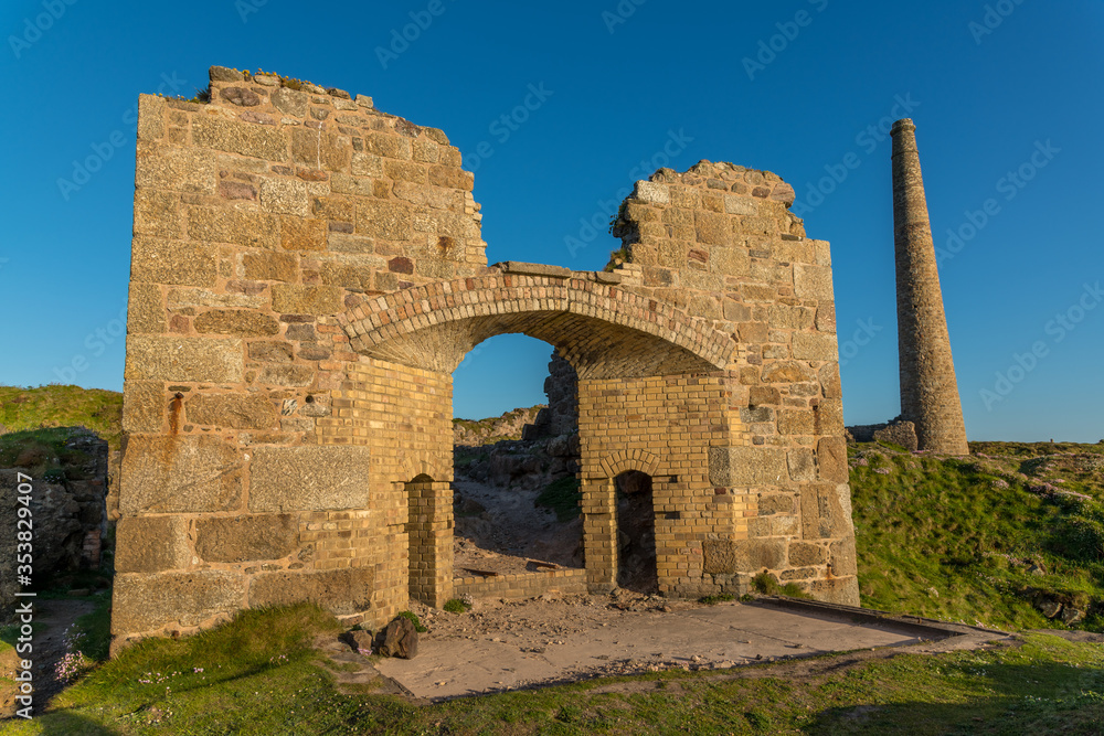 The old arched entrance to Brunton calciner, with tin mine chimney, at Botallack, Cornwall