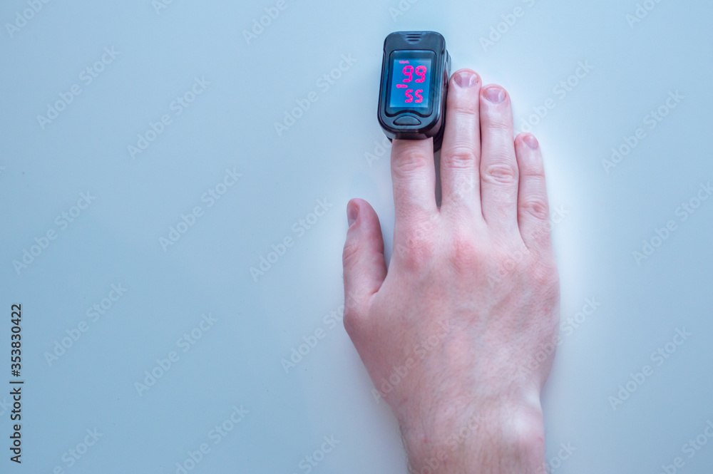 pulse oximeter is placed on the index finger of a man’s hand to measure saturation. Close-up. pulse oximeter is placed on the index finger of a man’s hand to measure saturation. Close-up.