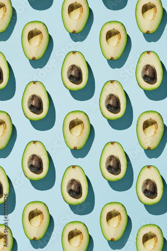 Vertical pattern of cut avocado on blue background, healthy eating concept