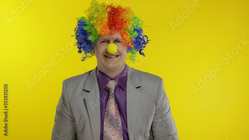 Clown businessman entrepreneur boss in wig at work. Halloween. Yellow background