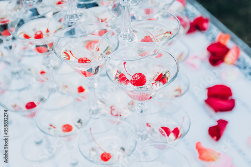 pyramid of champagne glasses at an outdoor celebration. A glass of champagne with a cherry.