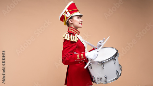 Foto Charming cheerful drummer in a red uniform, sings and plays the drum