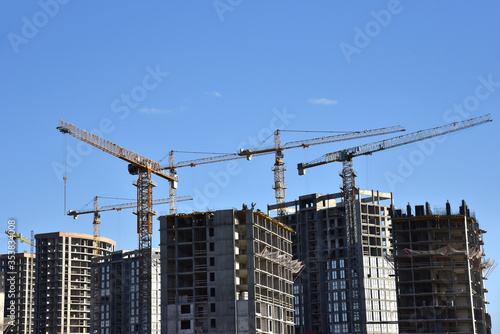 Tower crane constructing a new residential building at a construction site against blue sky. Renovation program, development, concept of the buildings industry.