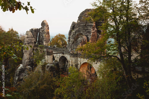 Bastei bridge and mountain view. Narrow rock, natural sandstone arch in Europe. Hill scenery with greenery, sky and sunlight. photo