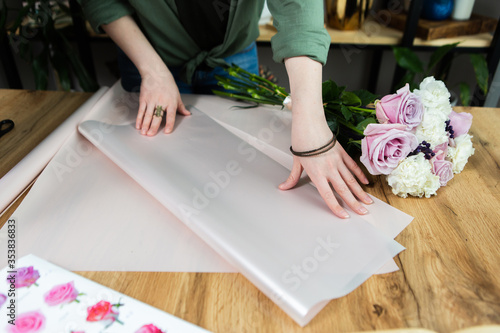 Women's hands with wrapping paper. Decorating in a gift and souvenir shop
