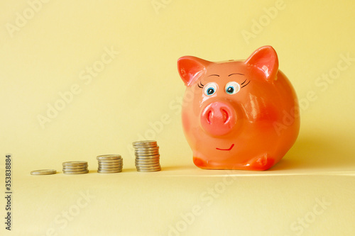 Piles of coins and piggy bank on a yellow background. Concept - saving money, accumulating finance, budget for a rainy day.