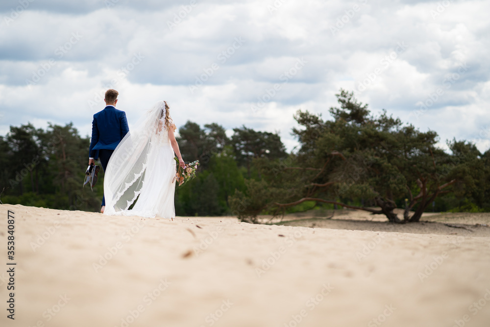 Wedding couple walking across sand dunes barefoot Wedding couple walking across sand dunes barefoot