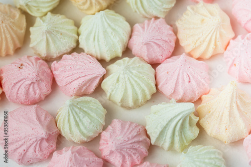 Colorful meringue sweets dessert on white background. Yellow mint green and pink