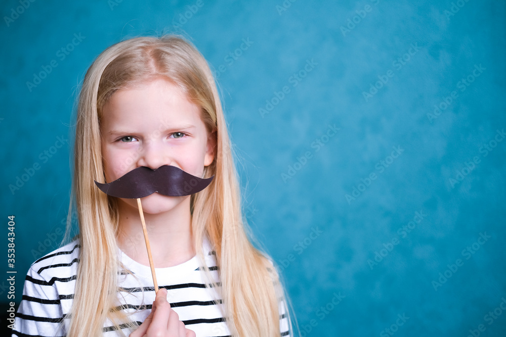 funny child blonde girl with mustache on blue background. Copyspace. Happy father day funny child blonde girl with mustache on blue background. Copyspace. Happy father day