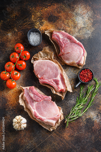 Raw pork meat from above on craft paper with ingredients for grill rosematy over rustic old metal background stock photo