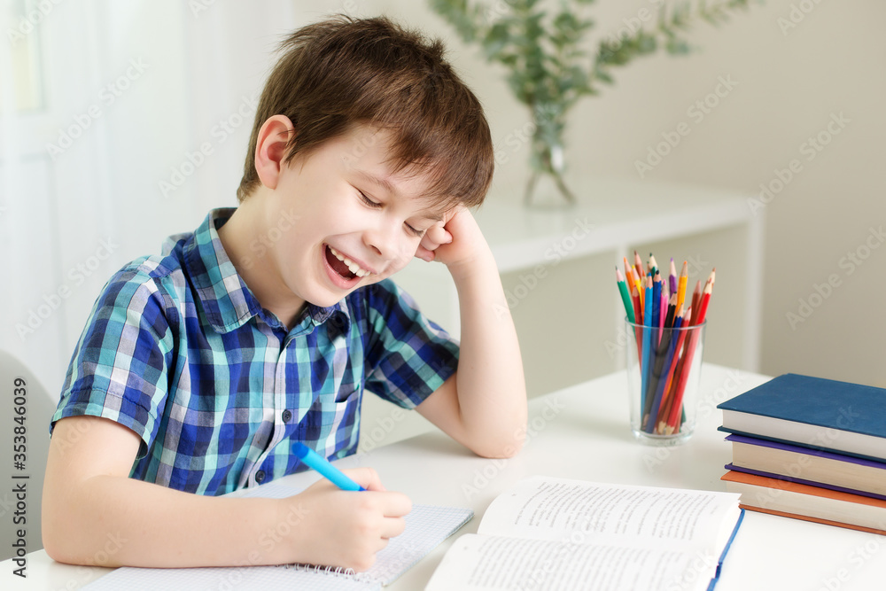 boy is sitting at the table, writing in a notebook, laughing boy is sitting at the table, writing in a notebook, laughing