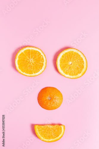  Smiling face made from slices of orange on a pink background. concept of healthy food, vitamin c and summer.