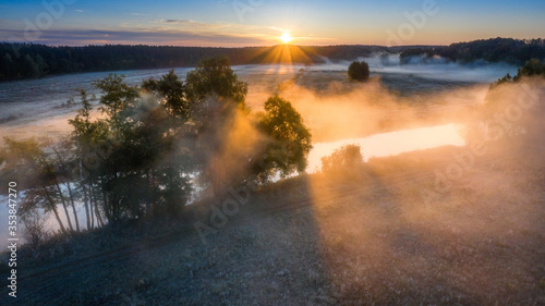 Summer scene aerial view. Misty sunrise. Foggy river in sunlight. Nature landscape.