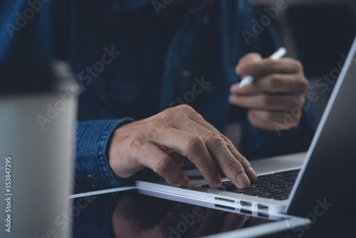 Business man working on laptop computer surfing internet at home office