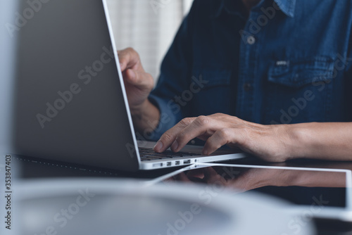 Man typing on laptop computer for online working surfing internet at home office