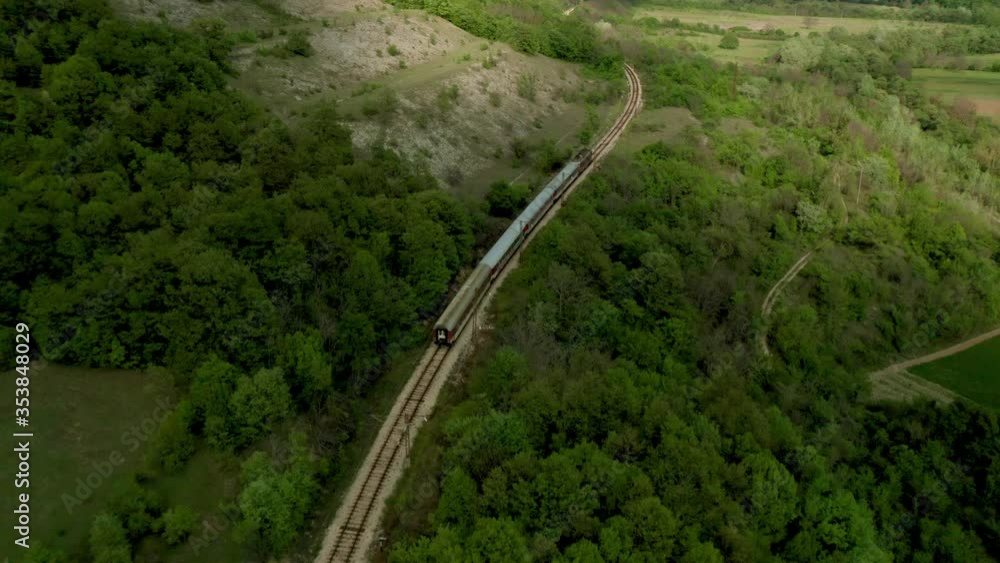 Aerial view of a passenger train crossing beautiful countryside in spring time. Aerial view of a passenger train crossing beautiful countryside in spring time.