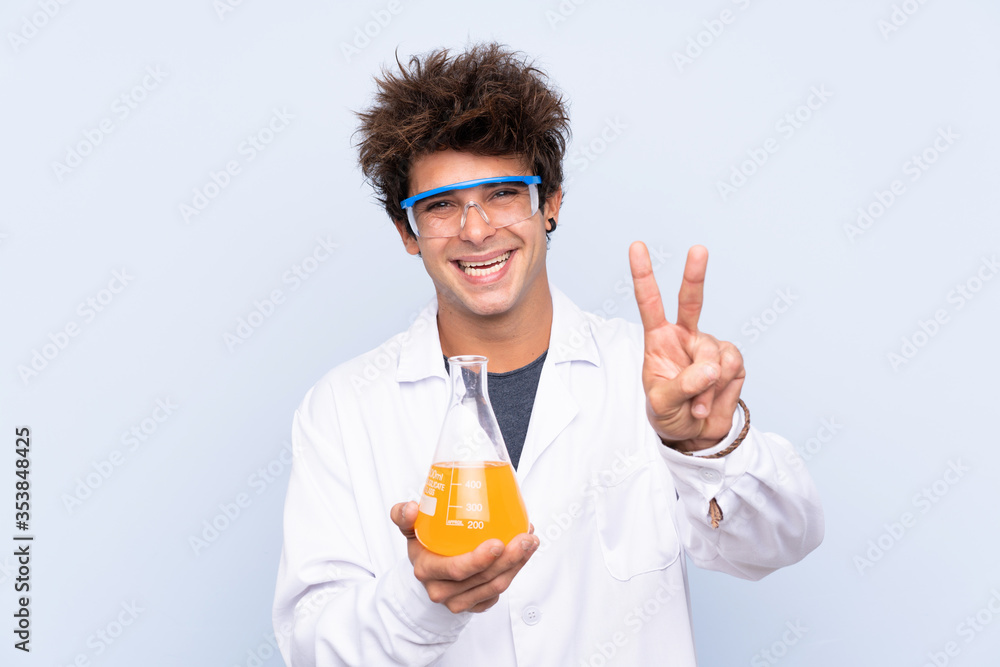 Young scientific man over isolated blue background smiling and showing victory sign Young scientific man over isolated blue background smiling and showing victory sign