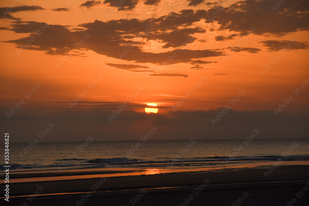 Amanecer en la playa con el sol entre las nubes Amanecer en la playa con el sol entre las nubes