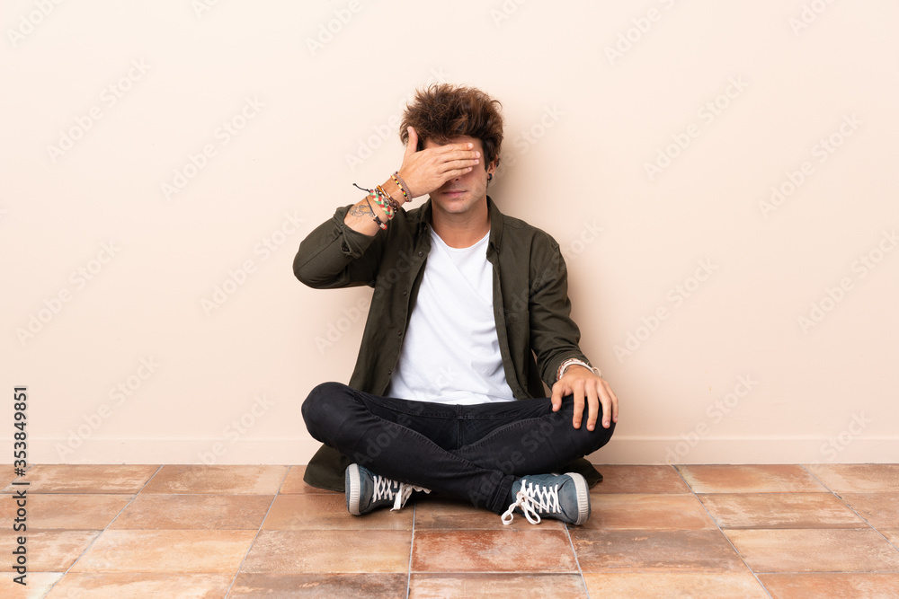 Young caucasian man sitting on the floor covering eyes by hands. Do not want to see something Young caucasian man sitting on the floor covering eyes by hands. Do not want to see something