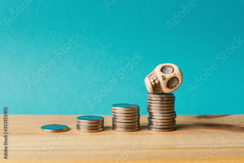 Piles of coins and a human skull on the highest pile. The concept is the accumulation of money and death.