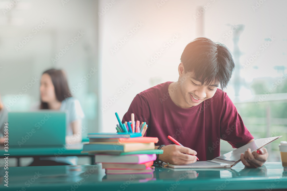 A young man reading and writtening book with many books, happy education university concept. A young man reading and writtening book with many books, happy education university concept.