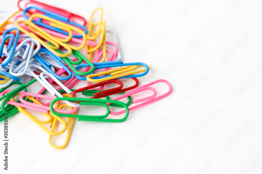 Multicolored paper clips on a white background. Close-up. Multicolored paper clips on a white background. Close-up.