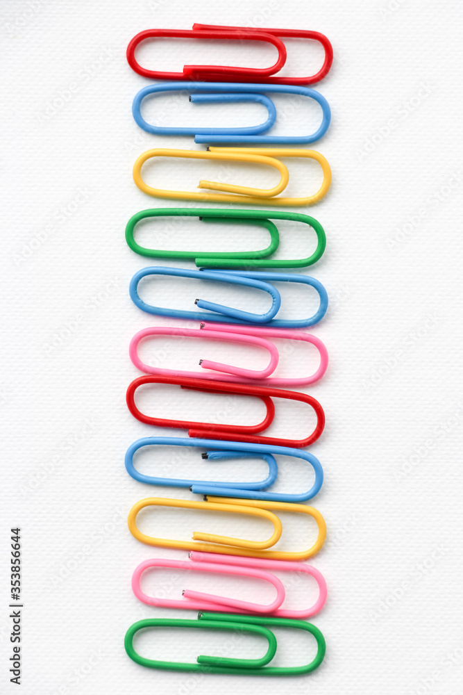 Multicolored paper clips on a white background. Close-up. 