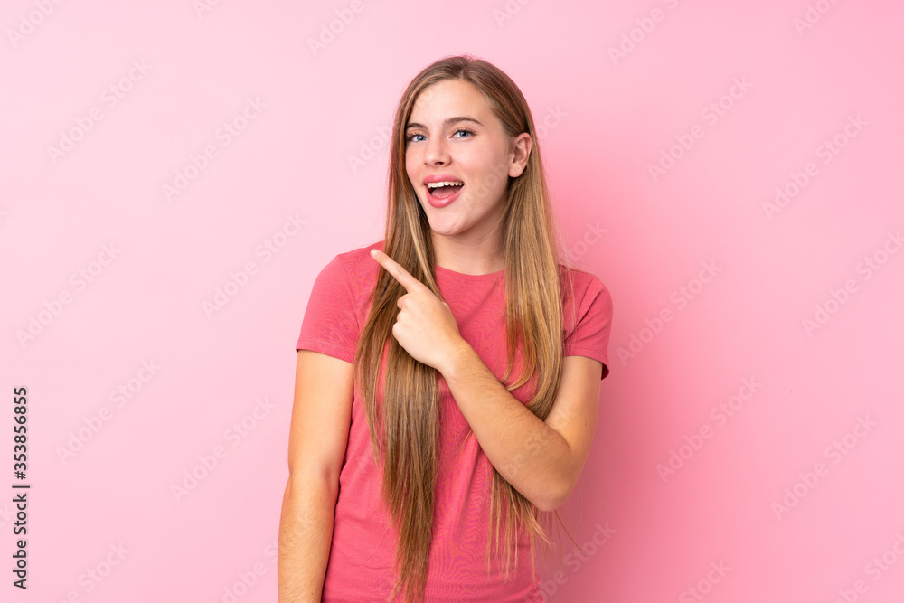 Teenager blonde girl over isolated pink background pointing finger to the side Teenager blonde girl over isolated pink background pointing finger to the side