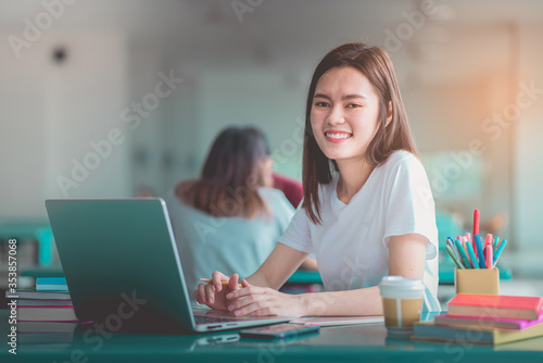 A young woman reading and writtening book with many books, happy education university concept.